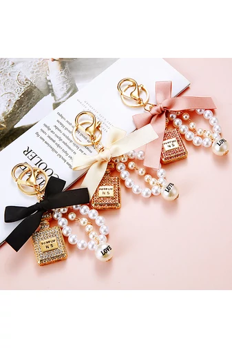  Elegancki brelok z zawieszką w kształcie butelki perfum z białymi kryształkami i czarną kokardką